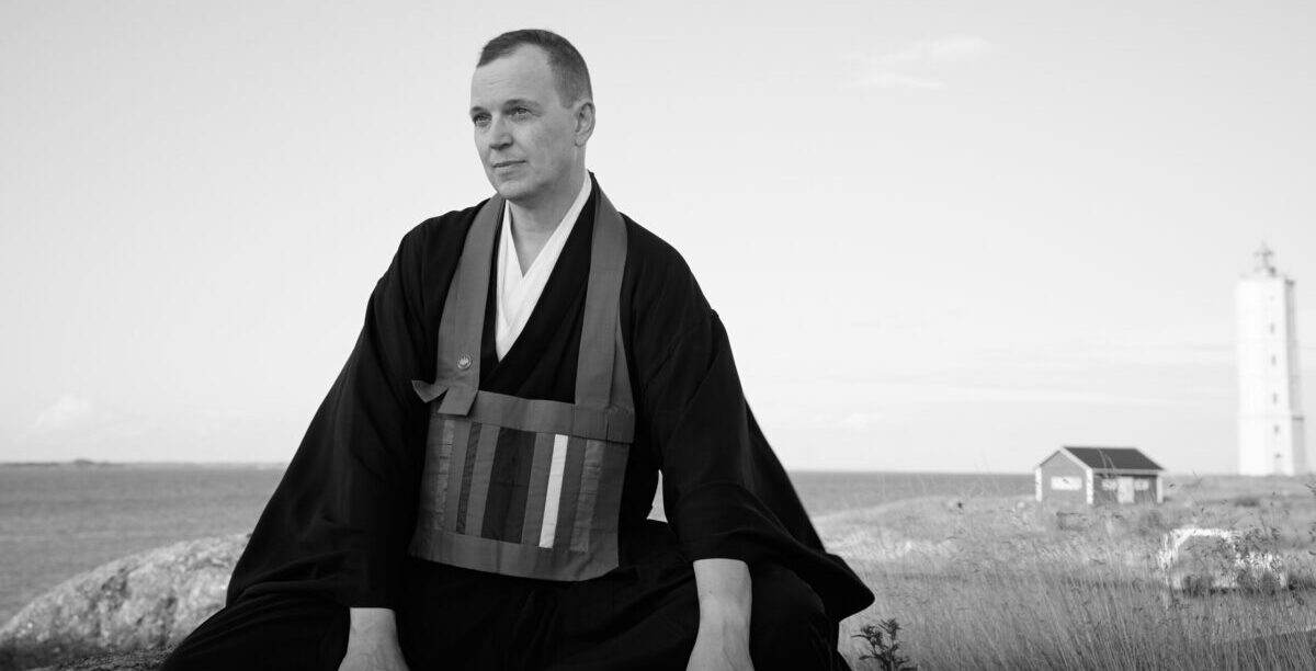 Sensei Mikko Ijäs sitting on an small island on the Baltic Sea with Söderskär lighthouse behind him